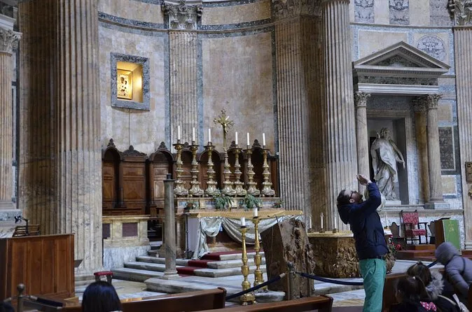 A side chapel altar in the Pantheon with a visitor photographing it from behind